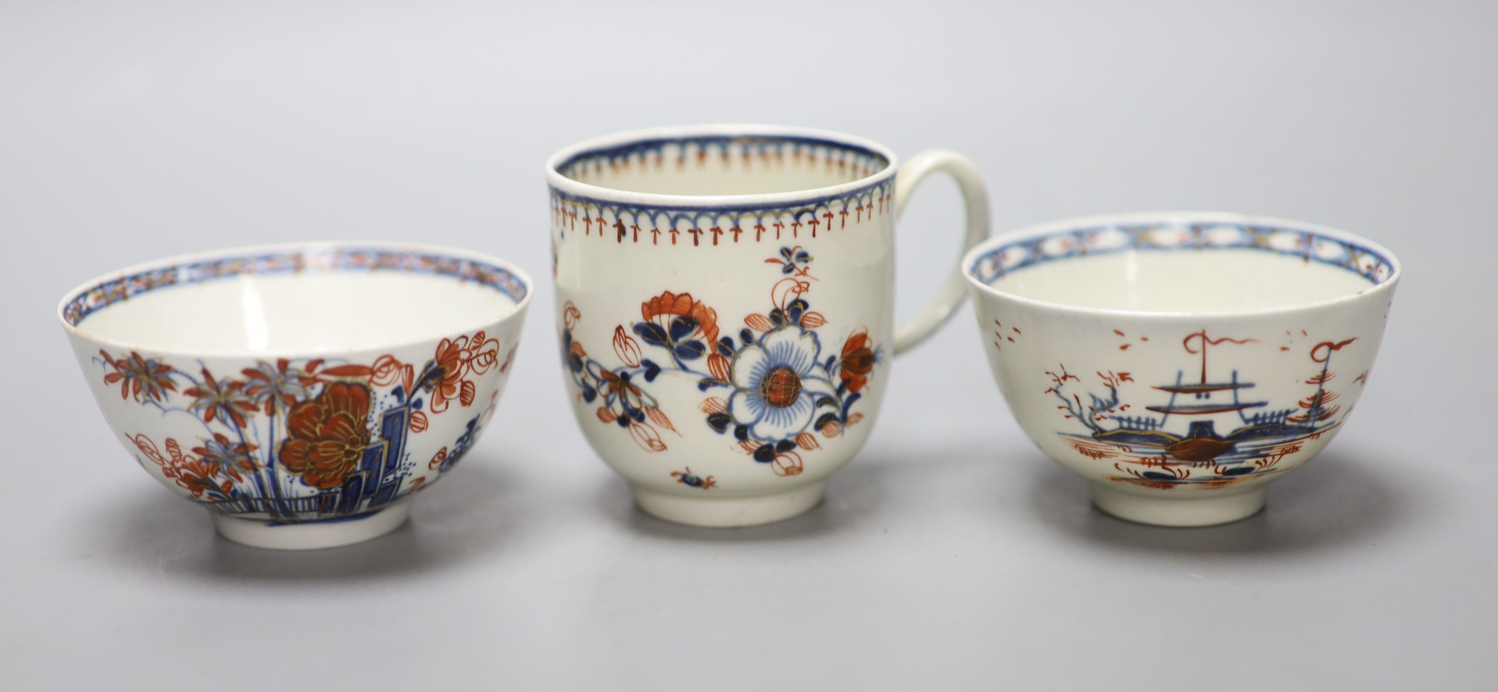 An 18th century Liverpool coffee cup and two teabowls, painted in blue with overglaze red highlights